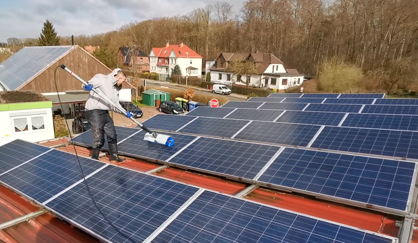 Mitarbeiter auf dem Dach eines Hauses bei der Reinigung einer Solaranlage