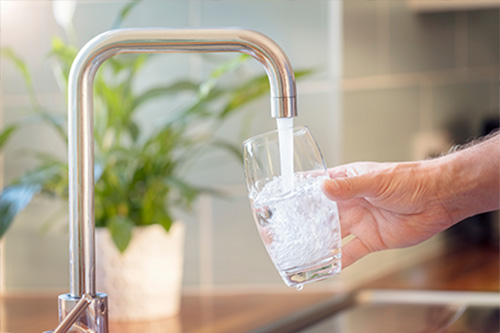 Auffüllen eines Glases mit Wasser aus dem Hahn